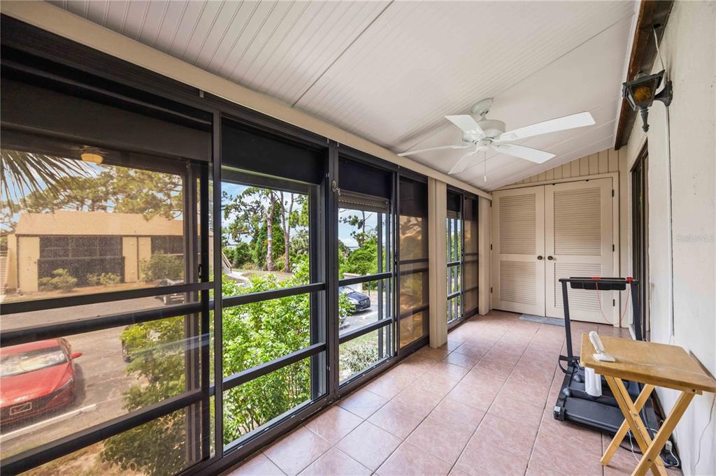 A screened-in porch with tile flooring, a ceiling fan, and a view of the parking lot — 18 QUAILS RUN BOULEVARD UNIT 18202, ENGLEWOOD, FL