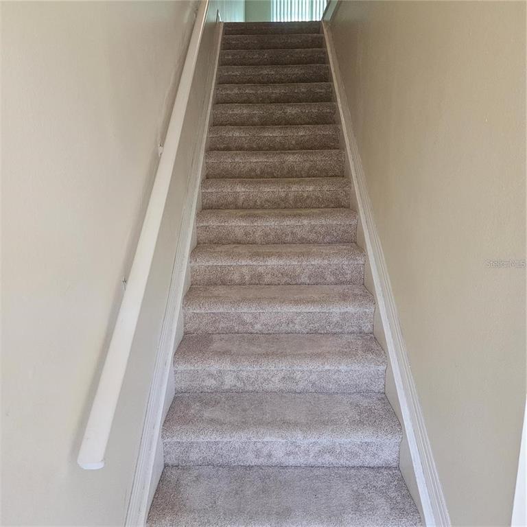 A straight staircase with beige carpet and a white handrail leads to an upper landing — 5500 BENTGRASS DRIVE UNIT 6-112, SARASOTA, FL