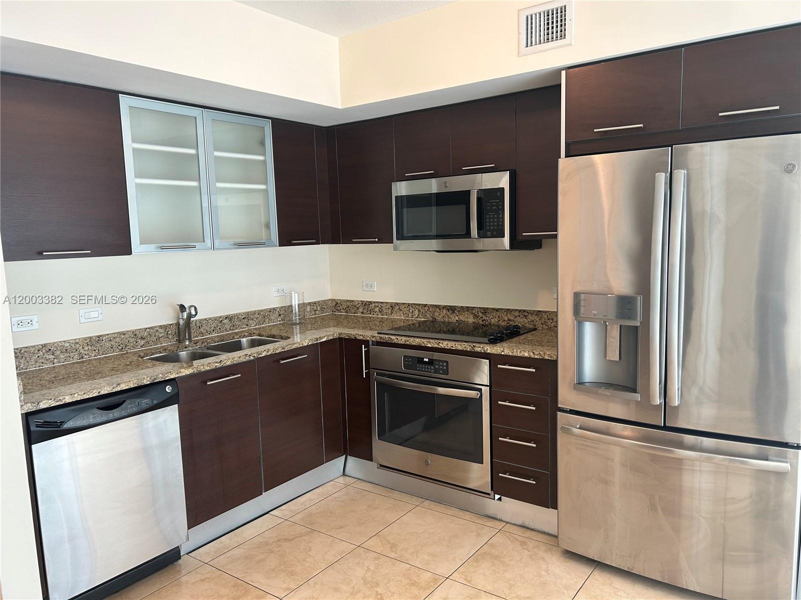 A kitchen features dark wood cabinets, stainless steel appliances, and granite countertops — 41 SE 5th St # 1108, Miami FL 33131, MIAMI, FL