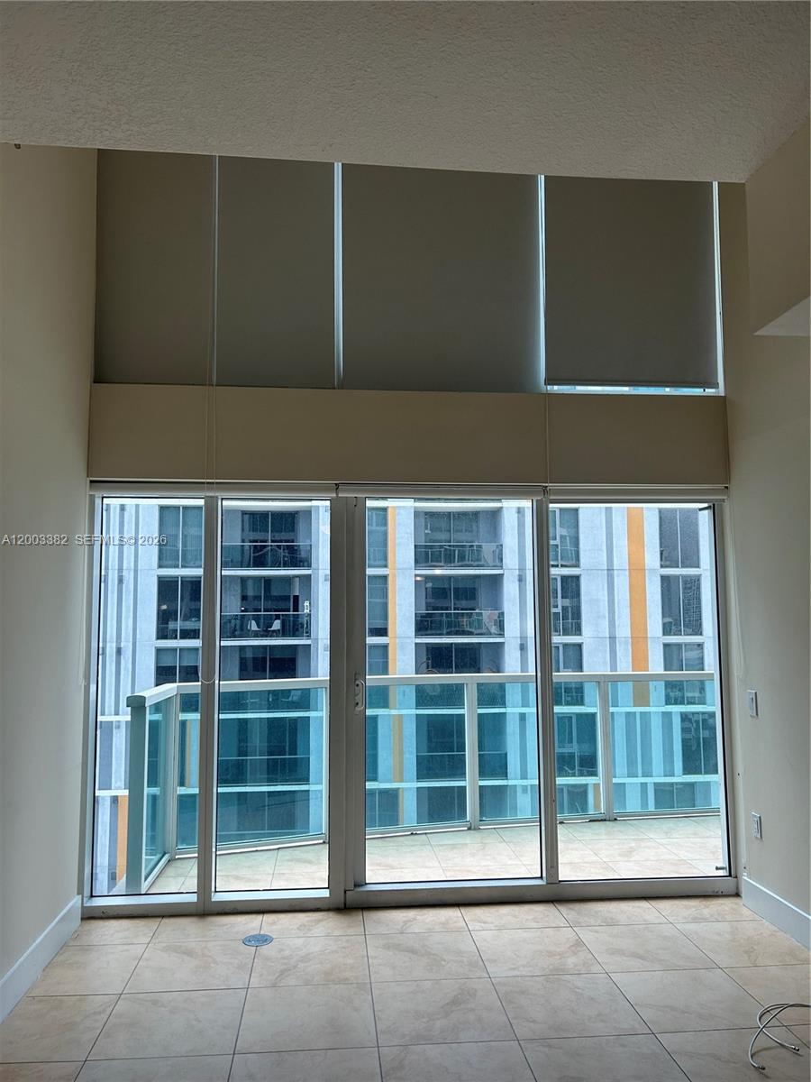 A room with tile flooring features floor-to-ceiling windows and a balcony overlooking another building — 41 SE 5th St # 1108, Miami FL 33131, MIAMI, FL