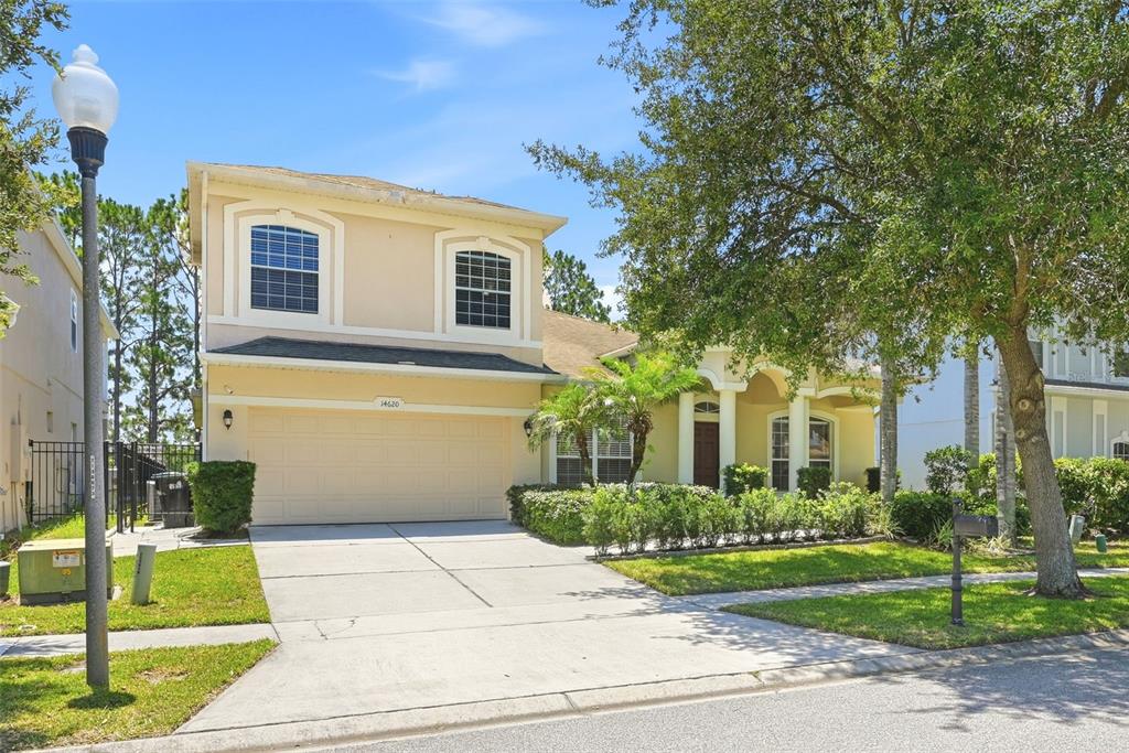 A two-story suburban house with a beige exterior, a two-car garage, and a paved driveway — 14620 CABLESHIRE WAY, ORLANDO, FL