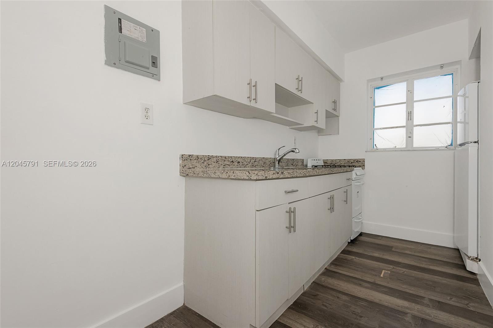 A kitchen features white cabinets, granite countertops, a sink, and a white refrigerator — 8340 Crespi Blvd # 20, Miami Beach FL 33141, MIAMI BEACH, FL