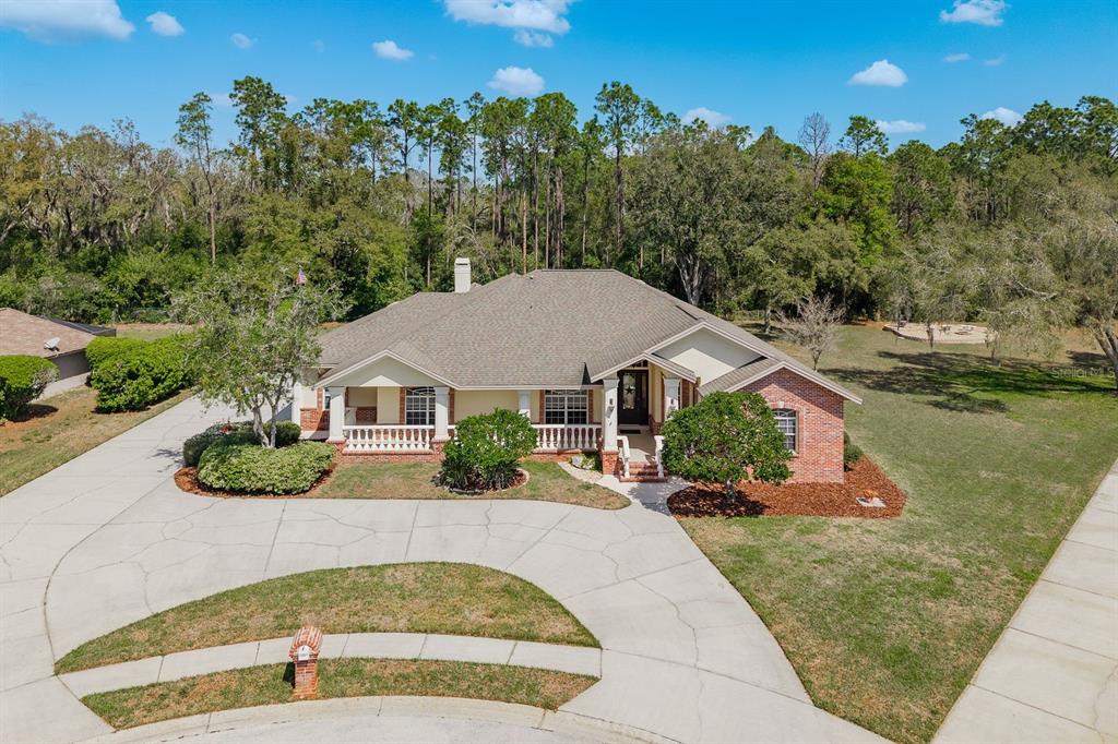 An aerial view shows a single-story house with a brick facade, porch, and concrete driveway — 6207 CLAIRE DE LUNE COURT, NEW PORT RICHEY, FL