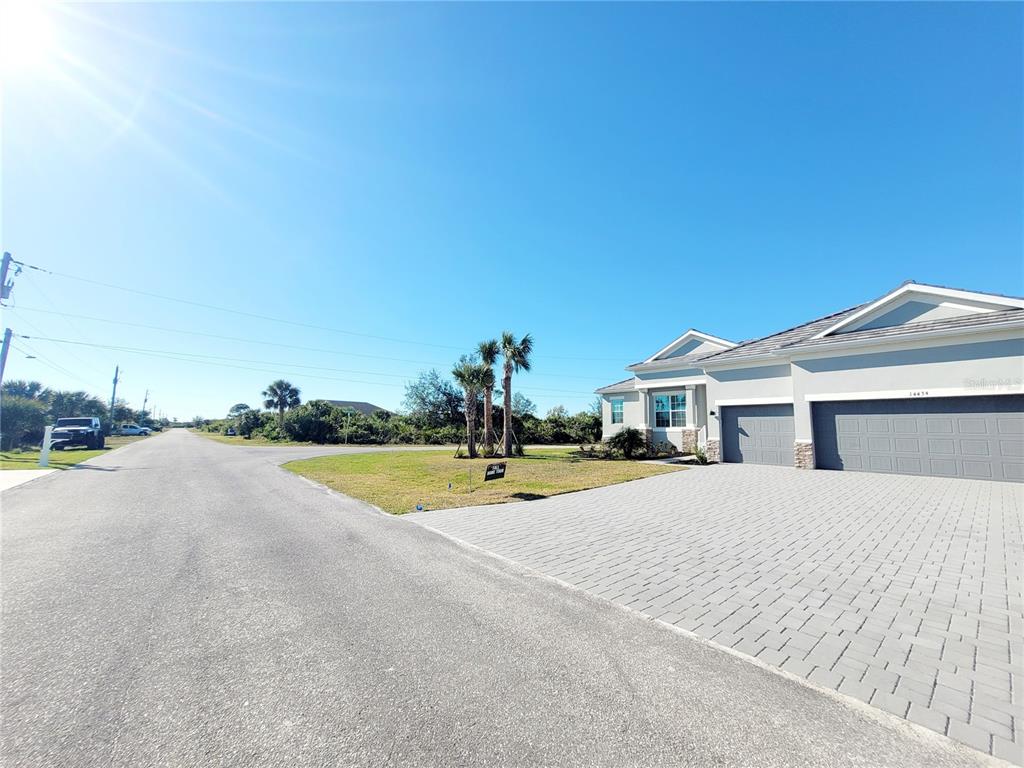 A modern house with a paved driveway and a three-car garage sits under a clear sky — 14442 AMESTOY AVENUE, PORT CHARLOTTE, FL