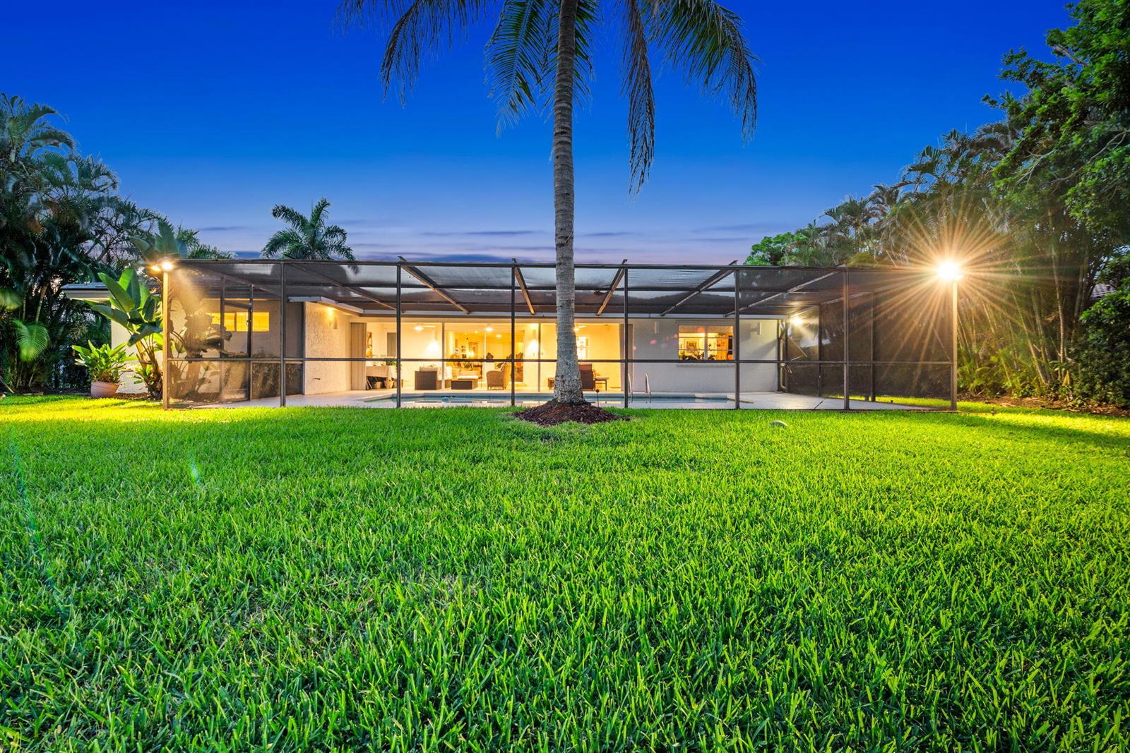 A backyard view of a house with a screened-in pool enclosure and a palm tree — 16731 Harbor Court, Weston FL 33326, WESTON, FL