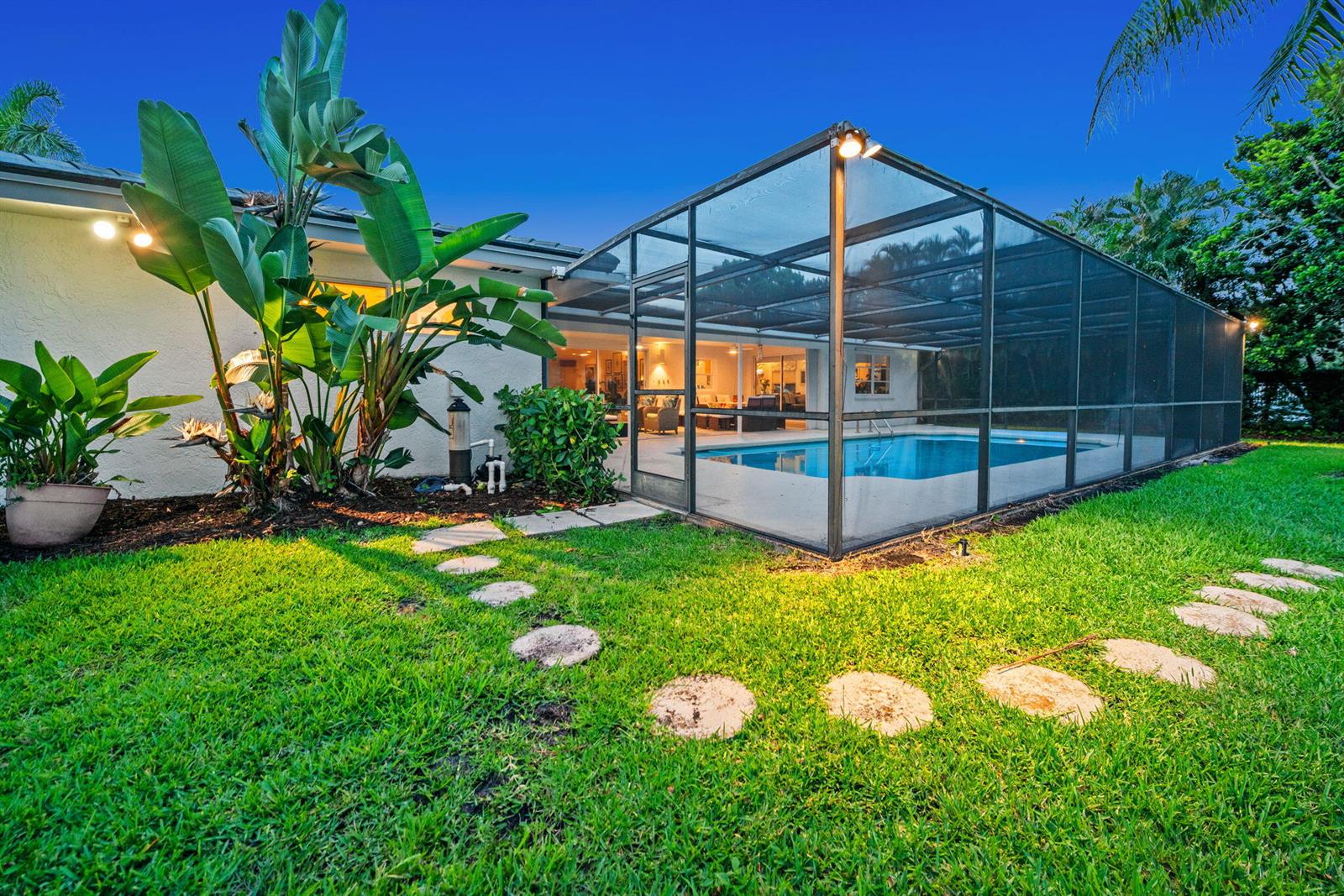 A backyard features a screened-in swimming pool, a stone path, and large tropical plants — 16731 Harbor Court, Weston FL 33326, WESTON, FL
