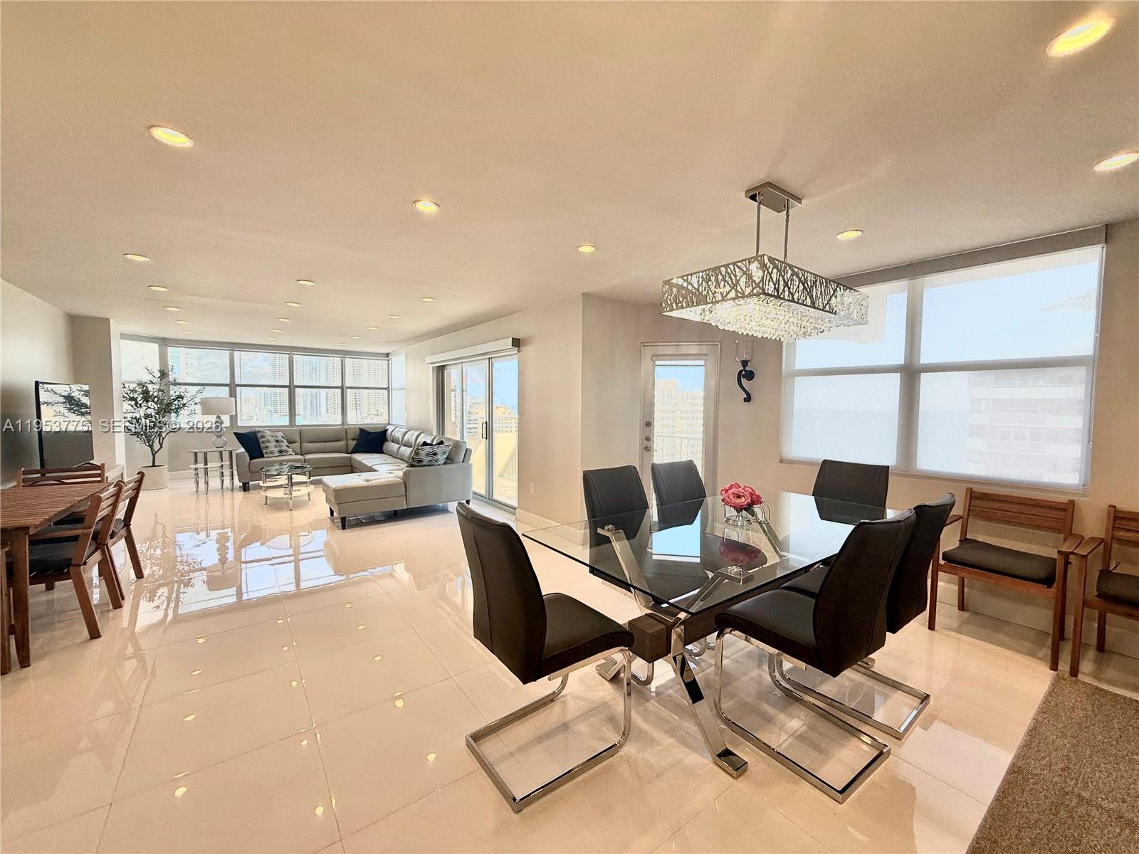 An open-concept living and dining area features white tile floors and floor-to-ceiling windows — 1985 S Ocean Dr # 22P, Hallandale Beach FL 33009, HALLANDALE BEACH, FL