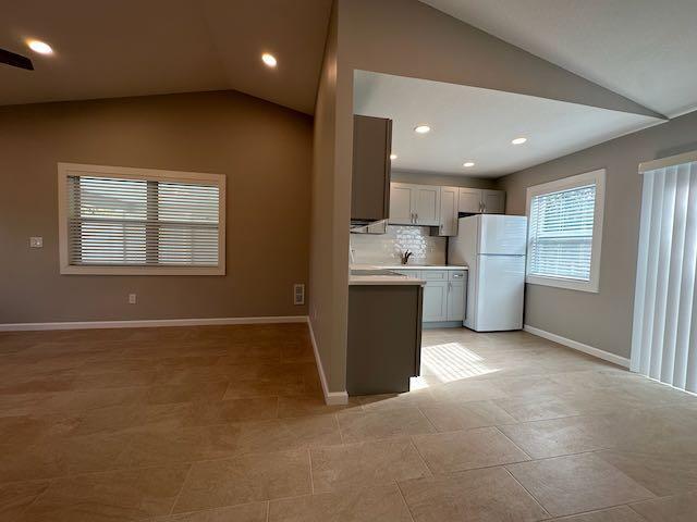 A kitchen with light cabinets and a white refrigerator opens to a tiled living area — 3166 SE Garden Street # 3166, Stuart FL 34997, STUART, FL
