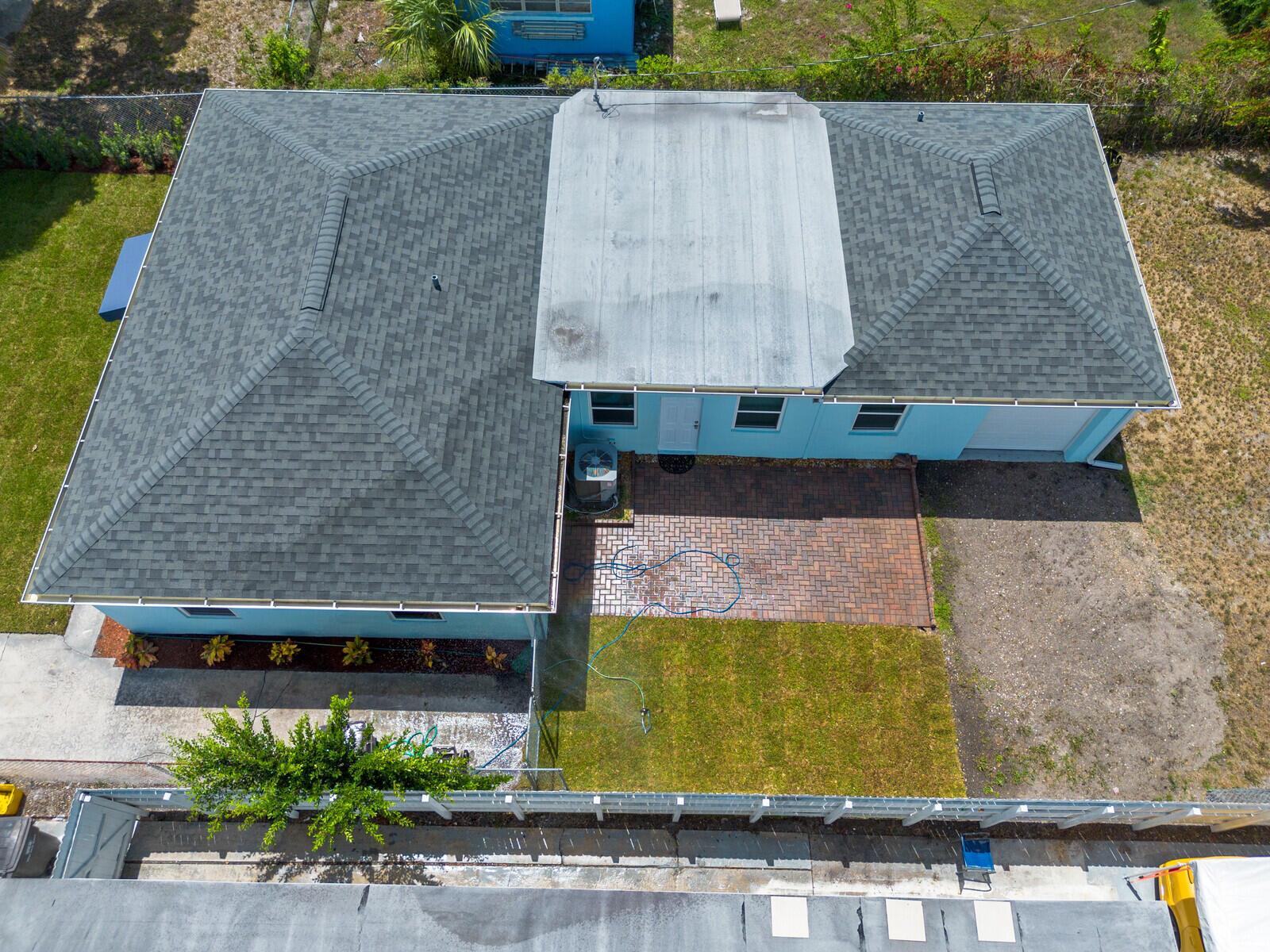 An aerial view shows a blue house with a shingled roof and a brick patio — 957 30th Street, West Palm Beach FL 33407, WEST PALM BEACH, FL
