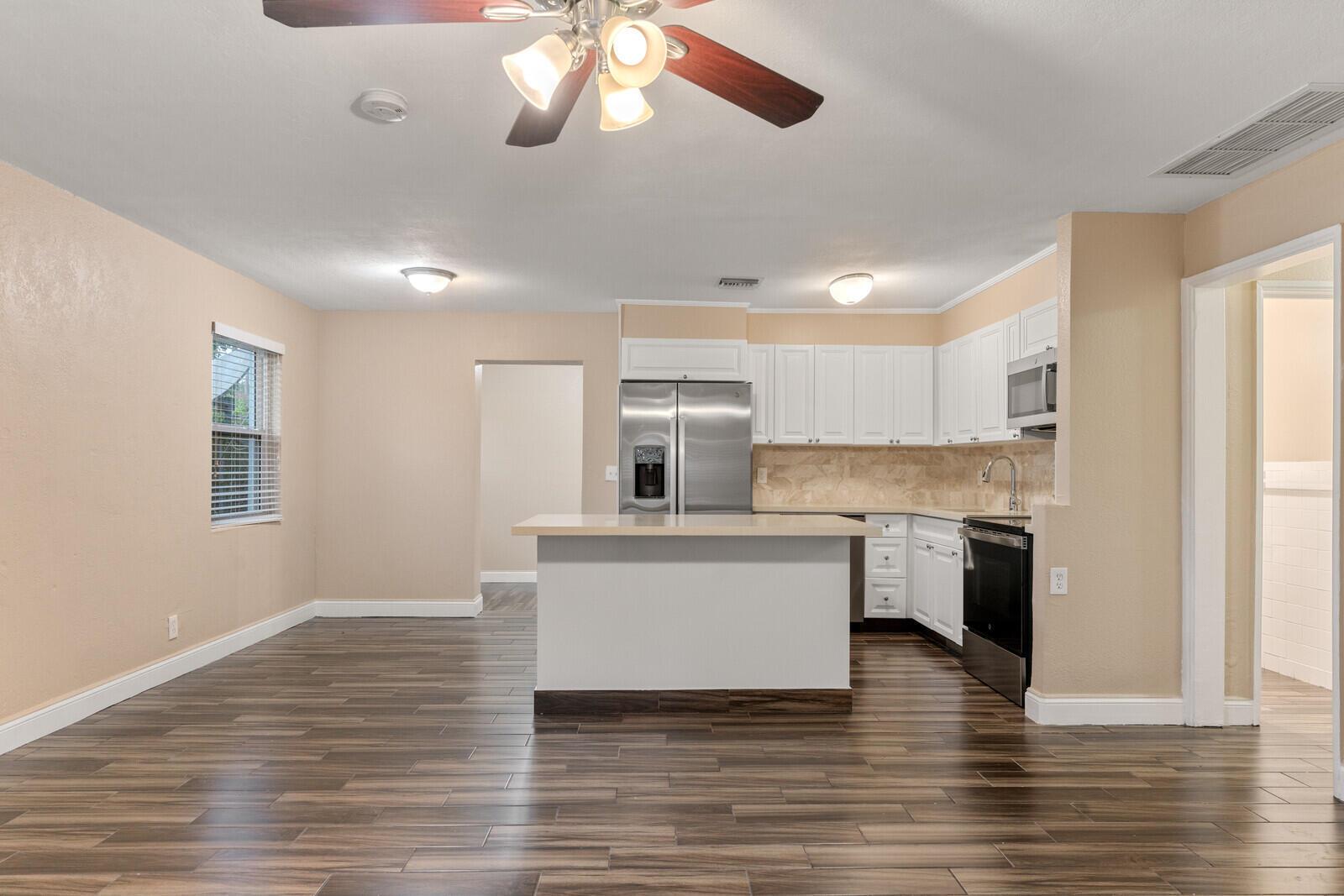 A kitchen with white cabinets, stainless steel appliances, and wood-look flooring in an open room — 957 30th Street, West Palm Beach FL 33407, WEST PALM BEACH, FL