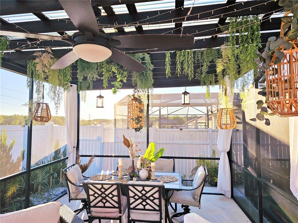 A screened-in patio features a dining set, hanging wicker lanterns, and a ceiling fan — 502 CANNA DRIVE, DAVENPORT, FL