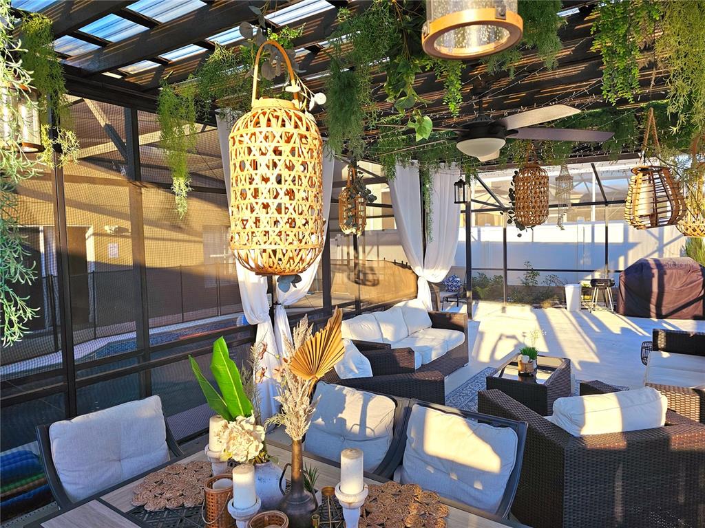 A covered outdoor patio features wicker furniture, hanging lanterns, and a ceiling fan — 502 CANNA DRIVE, DAVENPORT, FL