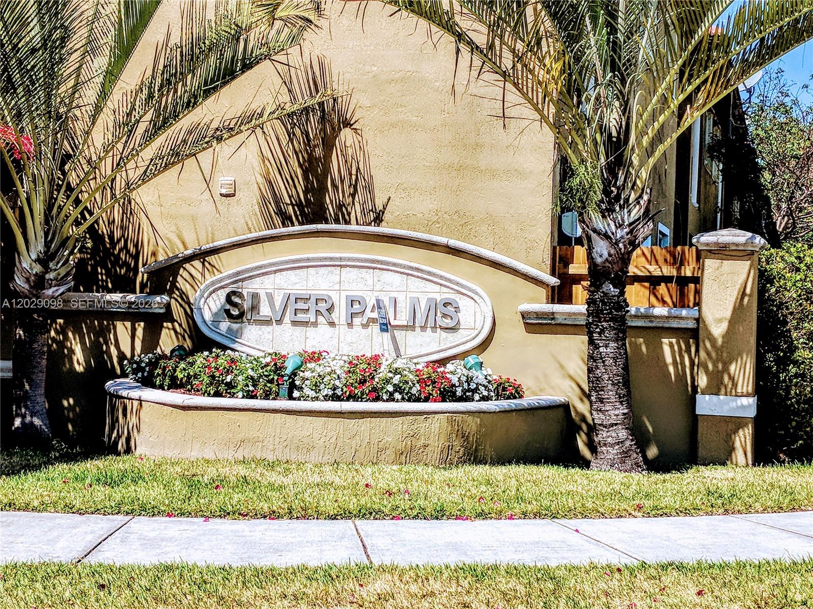 A stucco wall features a Silver Palms community sign surrounded by flowers and palm trees — 11262 SW 230th Ter # 11262, Miami FL 33170, MIAMI, FL
