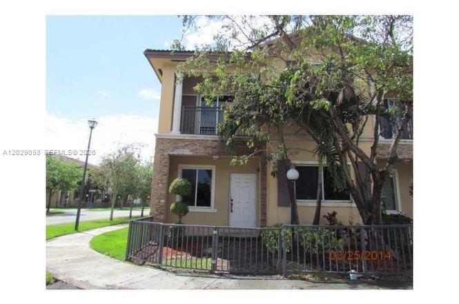 A two-story townhouse with a stone-accented facade, a small fenced yard, and a balcony — 11262 SW 230th Ter # 11262, Miami FL 33170, MIAMI, FL