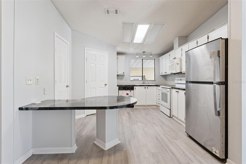 A kitchen with white cabinets, stainless steel appliances, a breakfast bar, and light wood flooring — 1787 W SCHWARTZ BOULEVARD, LADY LAKE, FL