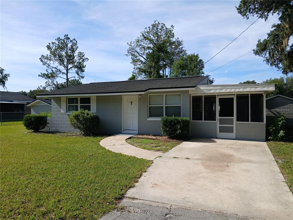 A single-story gray concrete block house with a front porch and a concrete driveway — 10424 E VICTORY LANE, INVERNESS, FL