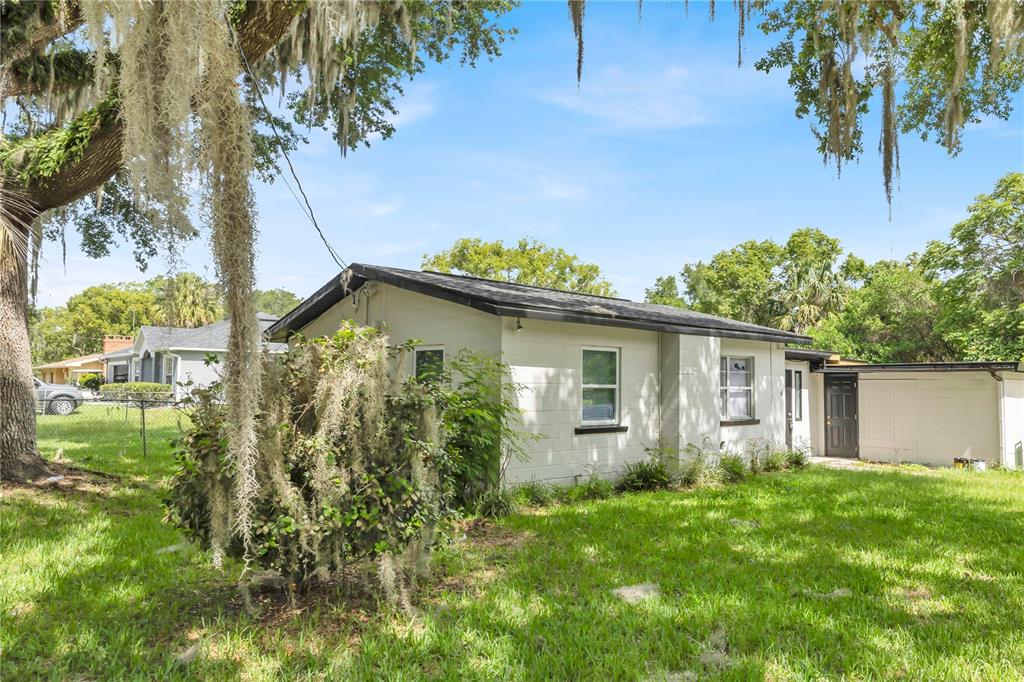 A white concrete block house with a dark roof sits on a grassy lot — 226 S HILL AVENUE, DELAND, FL