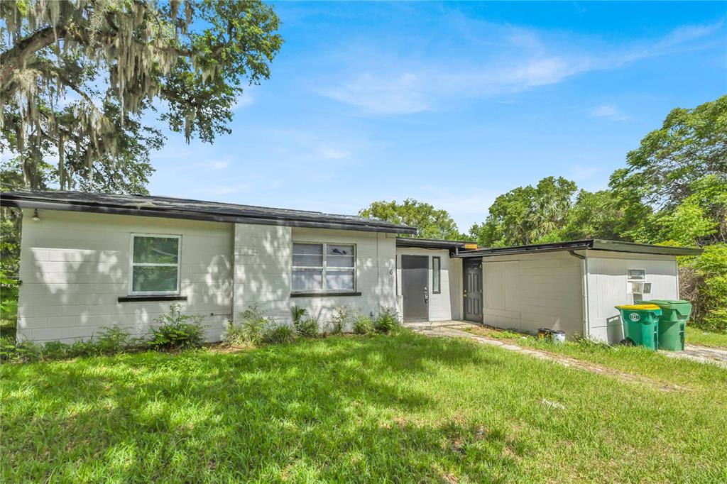 A single-story white house with a flat roof and two green trash bins outside — 226 S HILL AVENUE, DELAND, FL