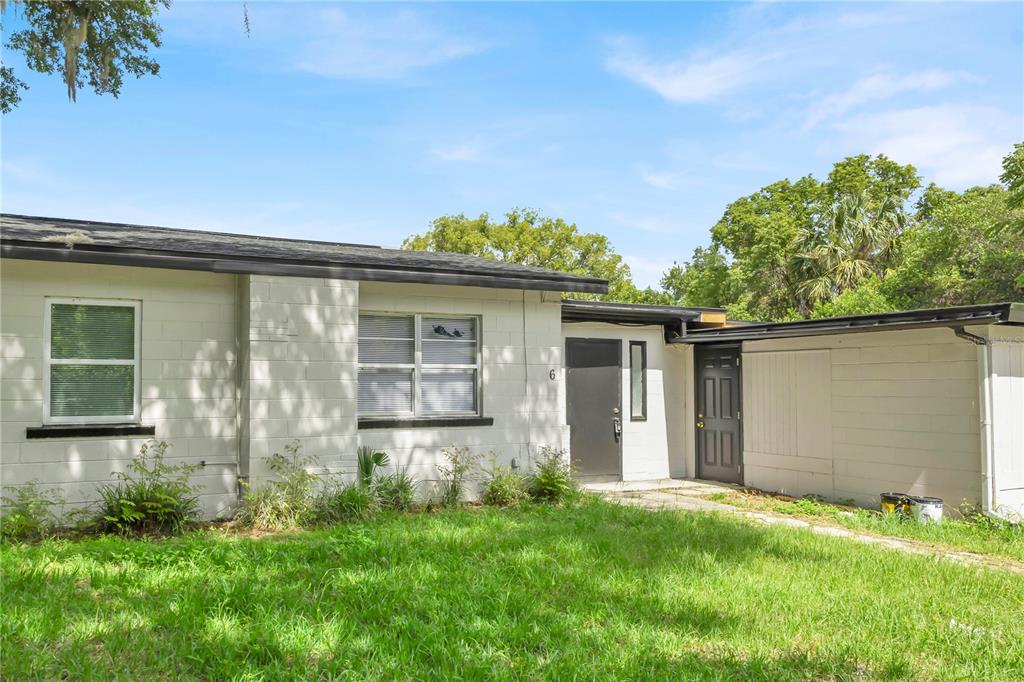 A single-story white concrete block house with a flat roof and two dark entry doors — 226 S HILL AVENUE, DELAND, FL