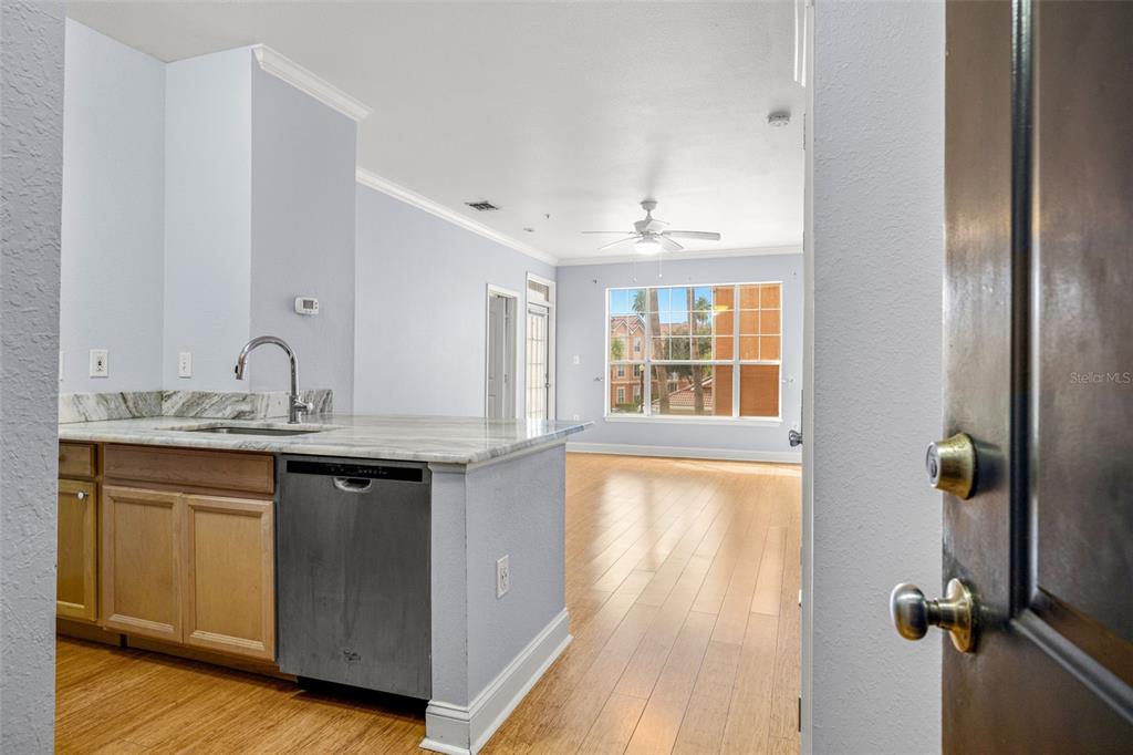 A kitchen with light wood cabinets and stone countertops overlooks a living area with flooring — 5000 CULBREATH KEY WAY UNIT 1-205, TAMPA, FL