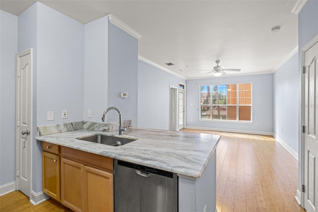 A kitchen island with a stainless steel sink and dishwasher overlooks a light-filled living area — 5000 CULBREATH KEY WAY UNIT 1-205, TAMPA, FL
