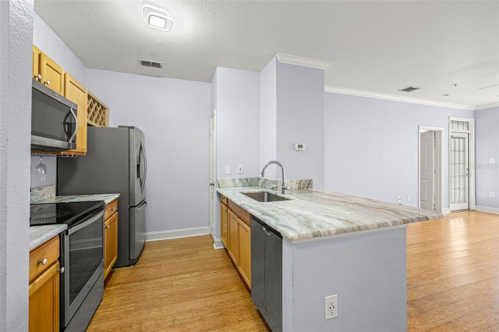A kitchen with wood cabinets, stainless steel appliances, and a stone countertop island — 5000 CULBREATH KEY WAY UNIT 1-205, TAMPA, FL