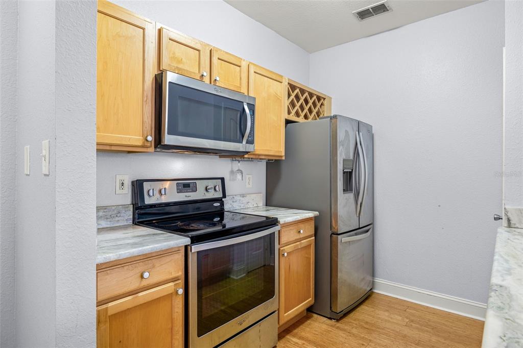 A kitchen features light wood cabinets, stainless steel appliances, and marble-patterned countertops — 5000 CULBREATH KEY WAY UNIT 1-205, TAMPA, FL