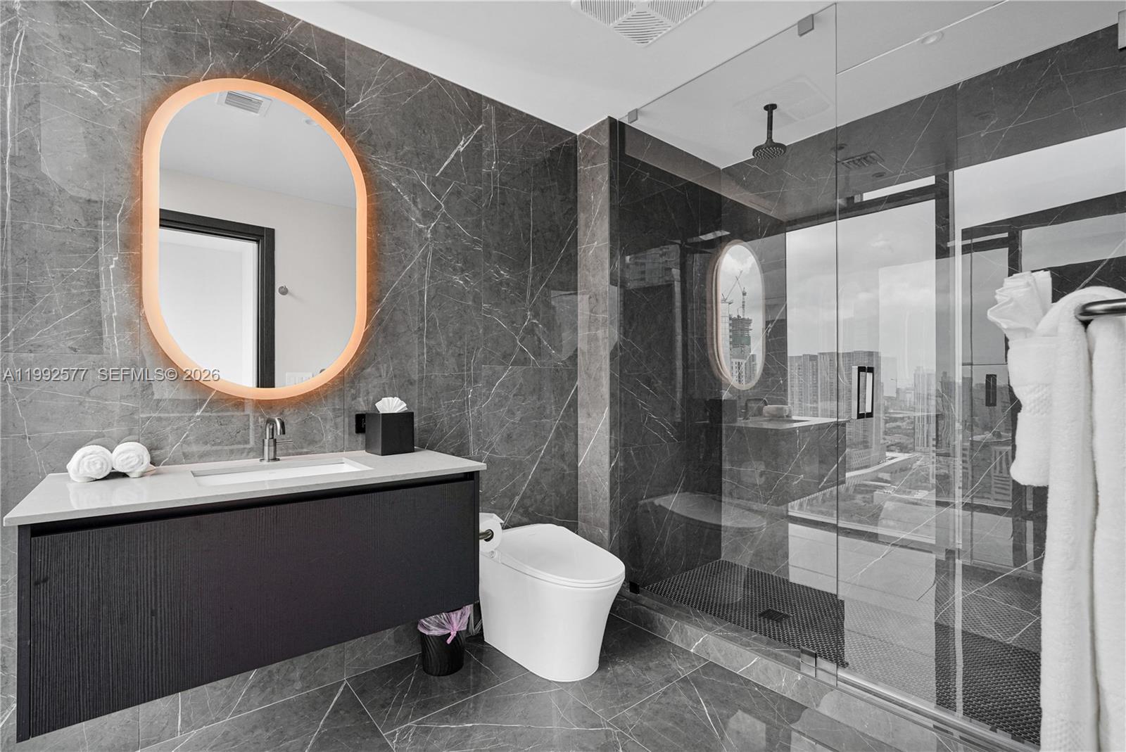 A modern bathroom features dark marble walls, a floating vanity, and a glass-enclosed shower — 20 NE 11th St # 2710, Miami FL 33132, MIAMI, FL