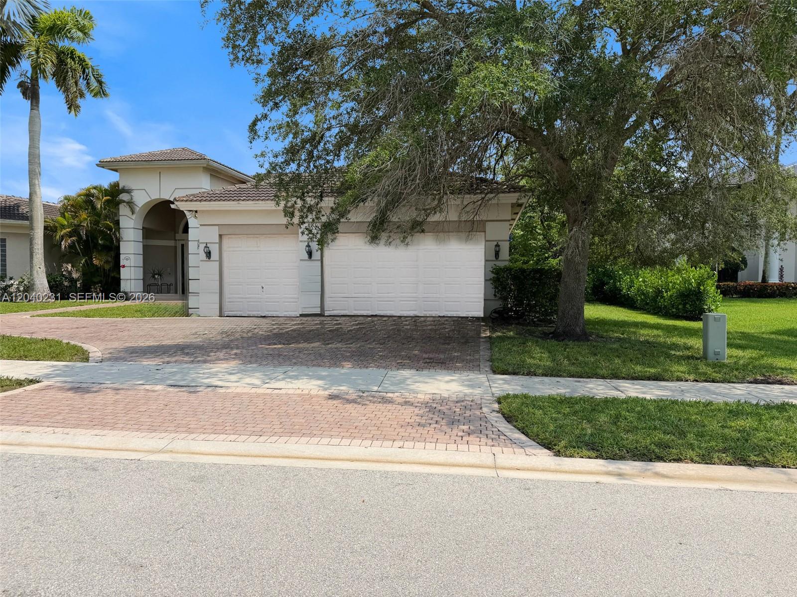 A single-story house features a three-car garage, a brick paver driveway, and mature landscaping — 15298 SW 34th St, Davie FL 33331, DAVIE, FL