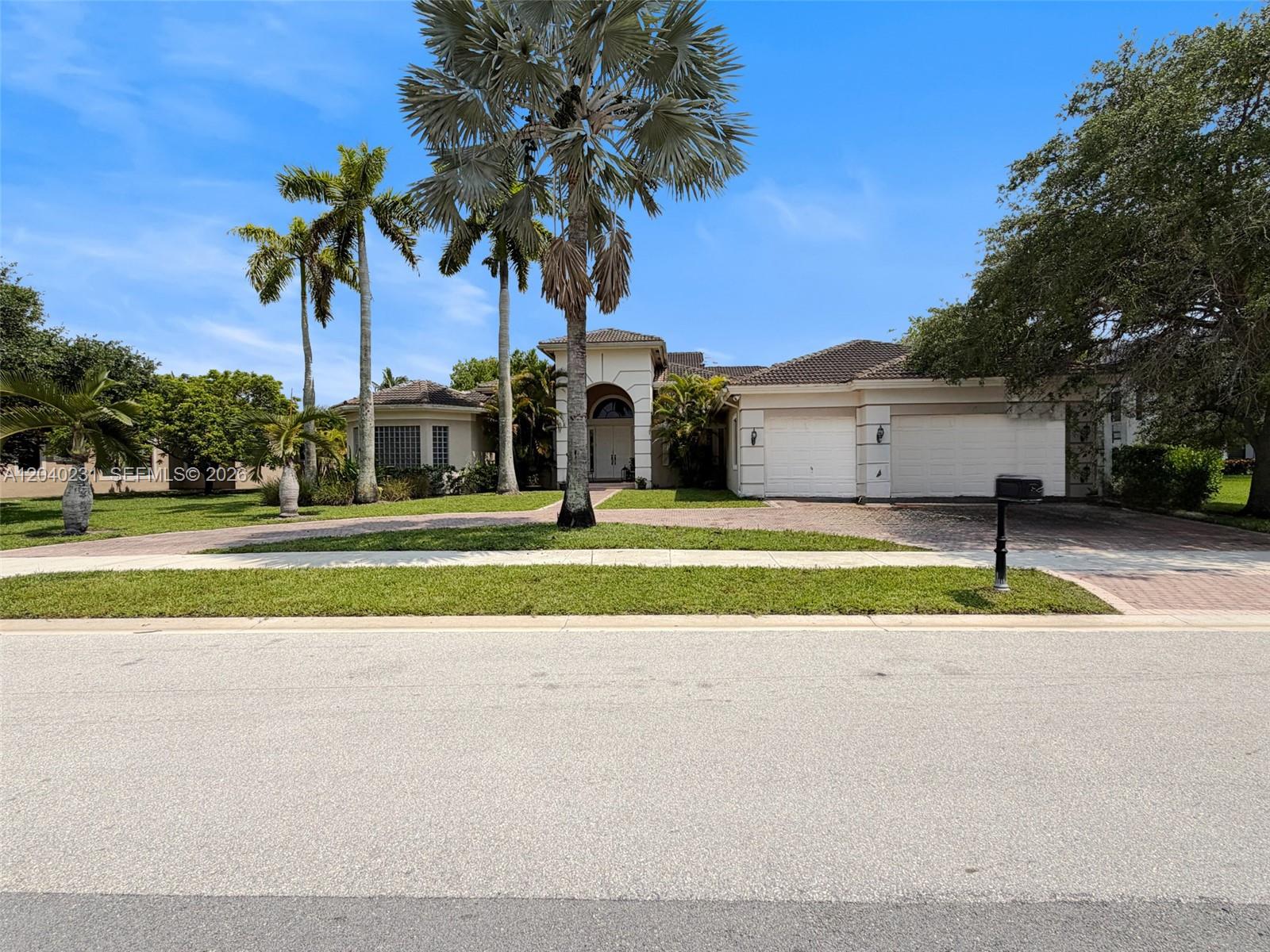 A single-story house with a paved driveway, palm trees, and a two-car garage — 15298 SW 34th St, Davie FL 33331, DAVIE, FL