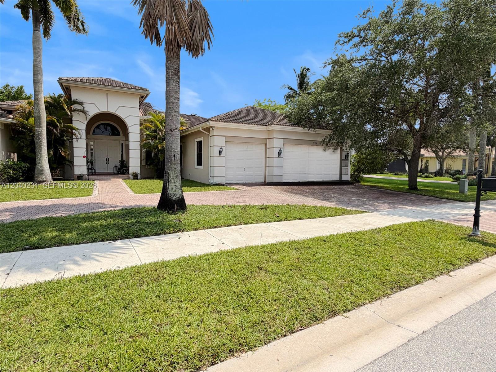 A beige house with a tiled roof, two-car garage, and a brick driveway — 15298 SW 34th St, Davie FL 33331, DAVIE, FL