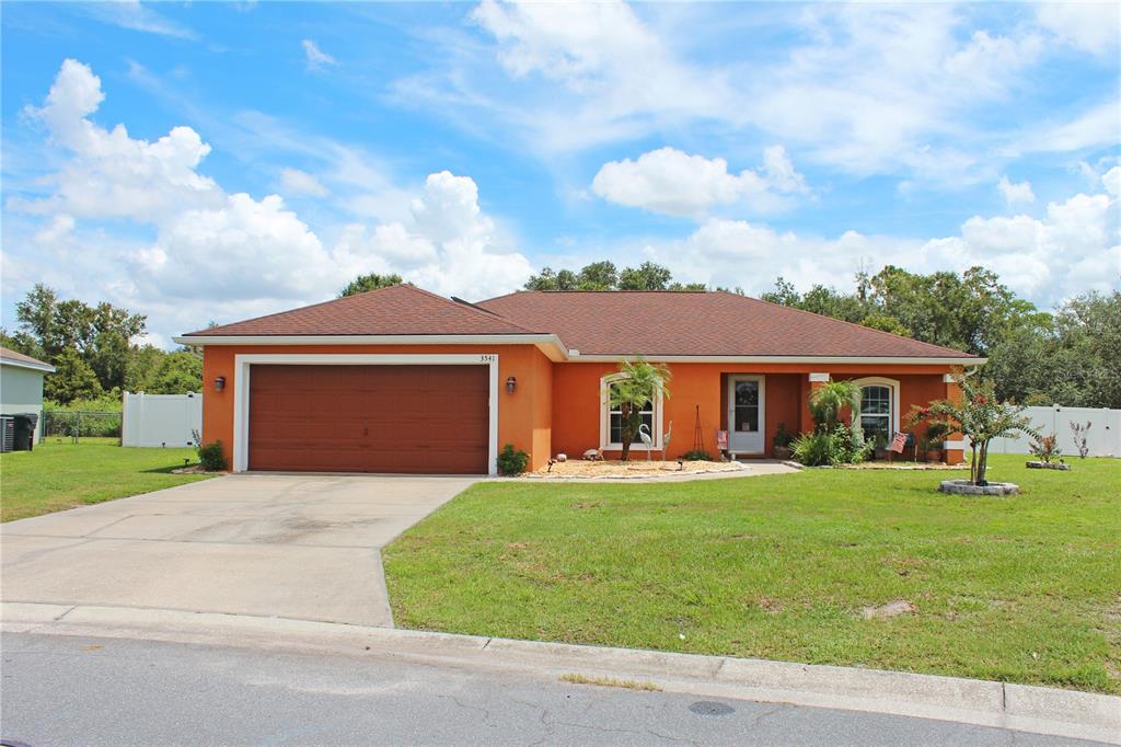 A single-story orange house with a brown roof and a two-car garage — 3541 MARSH WREN STREET, LAKELAND, FL