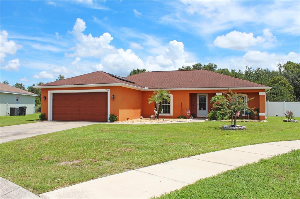 A single-story orange house with a brown roof, a two-car garage, and a front lawn — 3541 MARSH WREN STREET, LAKELAND, FL