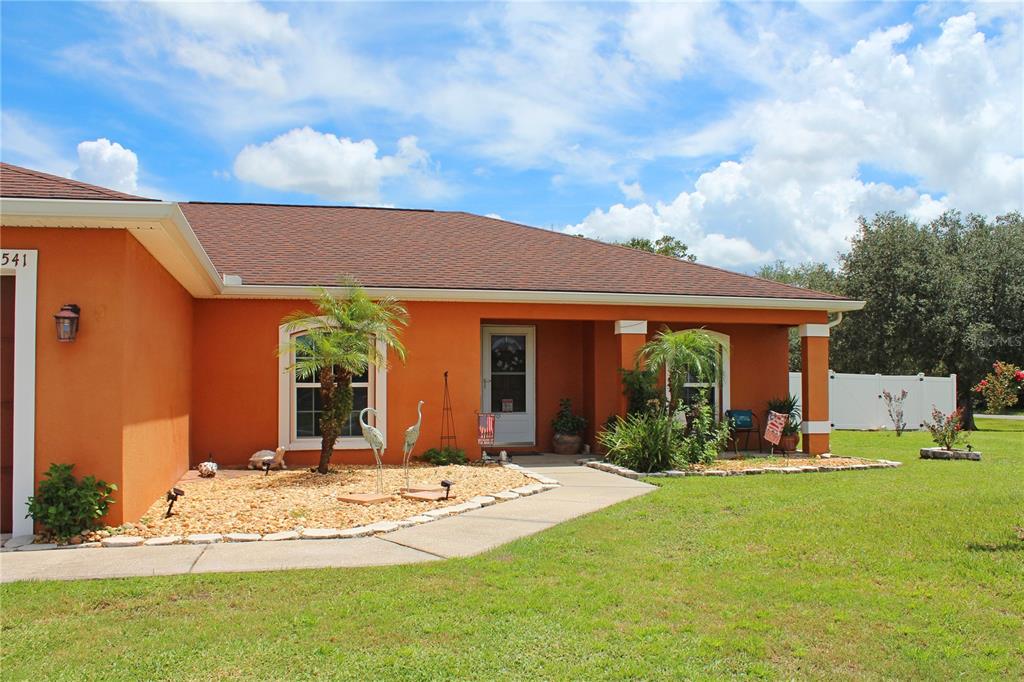 A single-story orange stucco house features a covered entryway, a concrete walkway, and landscaping — 3541 MARSH WREN STREET, LAKELAND, FL