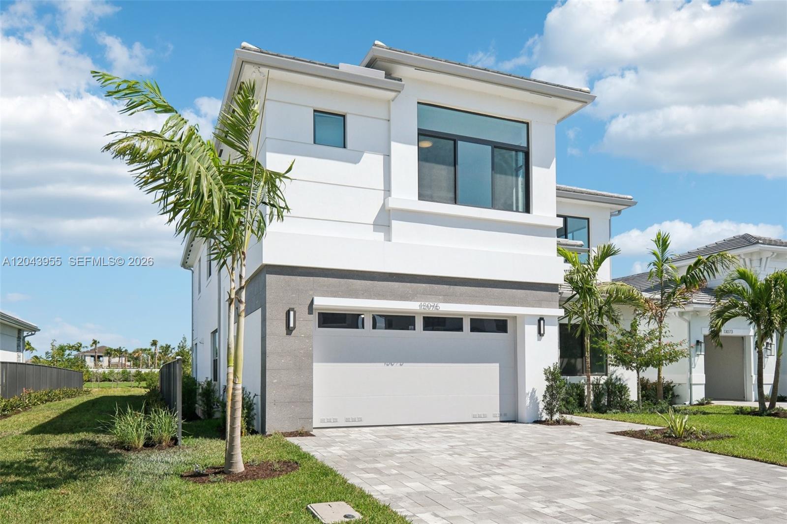 A two-story modern house features a white facade, gray stone accents, and a paved driveway — 13075 Feathering Way, Palm Beach Gardens FL 33412, PALM BEACH GARDENS, FL