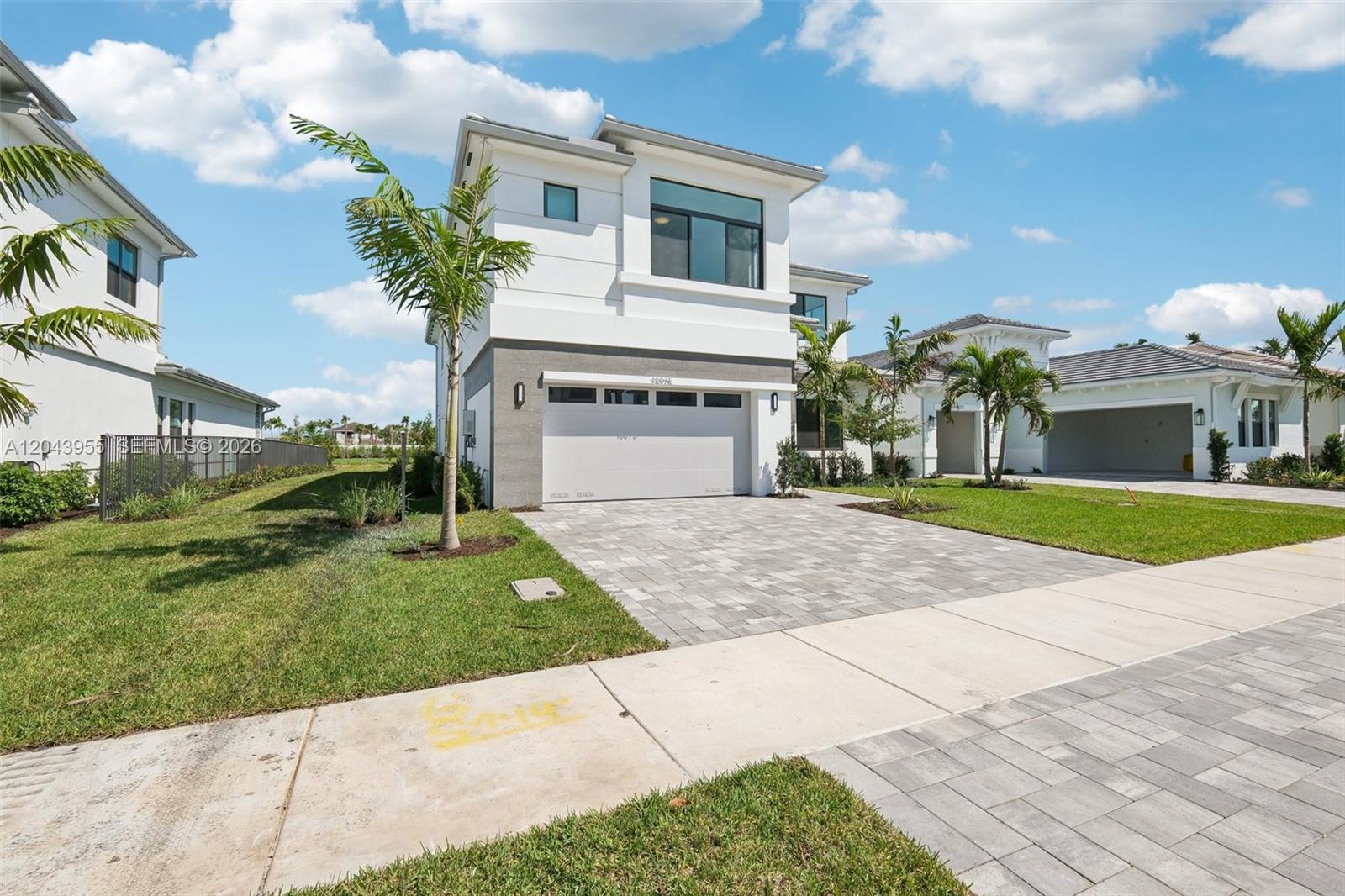 A two-story modern house with a white facade, gray stone accents, and a paved driveway — 13075 Feathering Way, Palm Beach Gardens FL 33412, PALM BEACH GARDENS, FL
