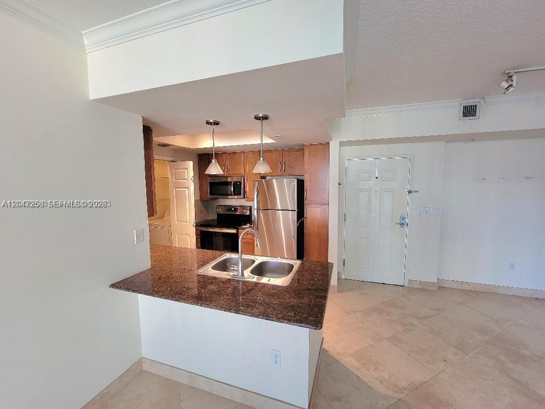 A kitchen features granite countertops, stainless steel appliances, and wood cabinets with a breakfast bar — 2000 N Bayshore Dr # 707, Miami FL 33137, MIAMI, FL
