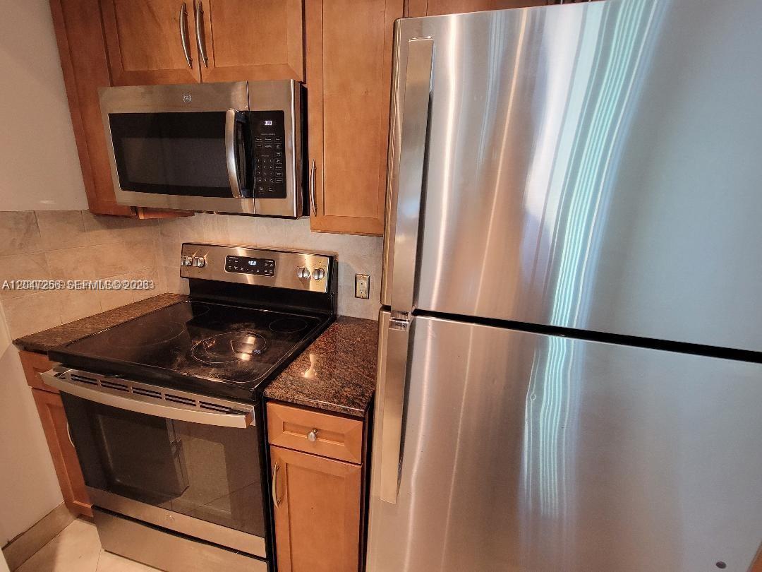 A kitchen features stainless steel appliances, wood cabinets, and dark granite countertops — 2000 N Bayshore Dr # 707, Miami FL 33137, MIAMI, FL
