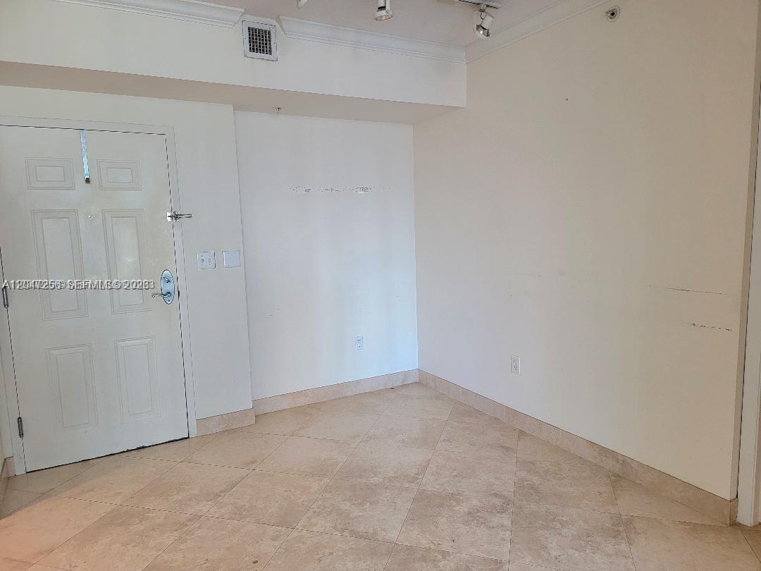 An empty room features beige tile flooring, white walls, a white door, and recessed lighting — 2000 N Bayshore Dr # 707, Miami FL 33137, MIAMI, FL