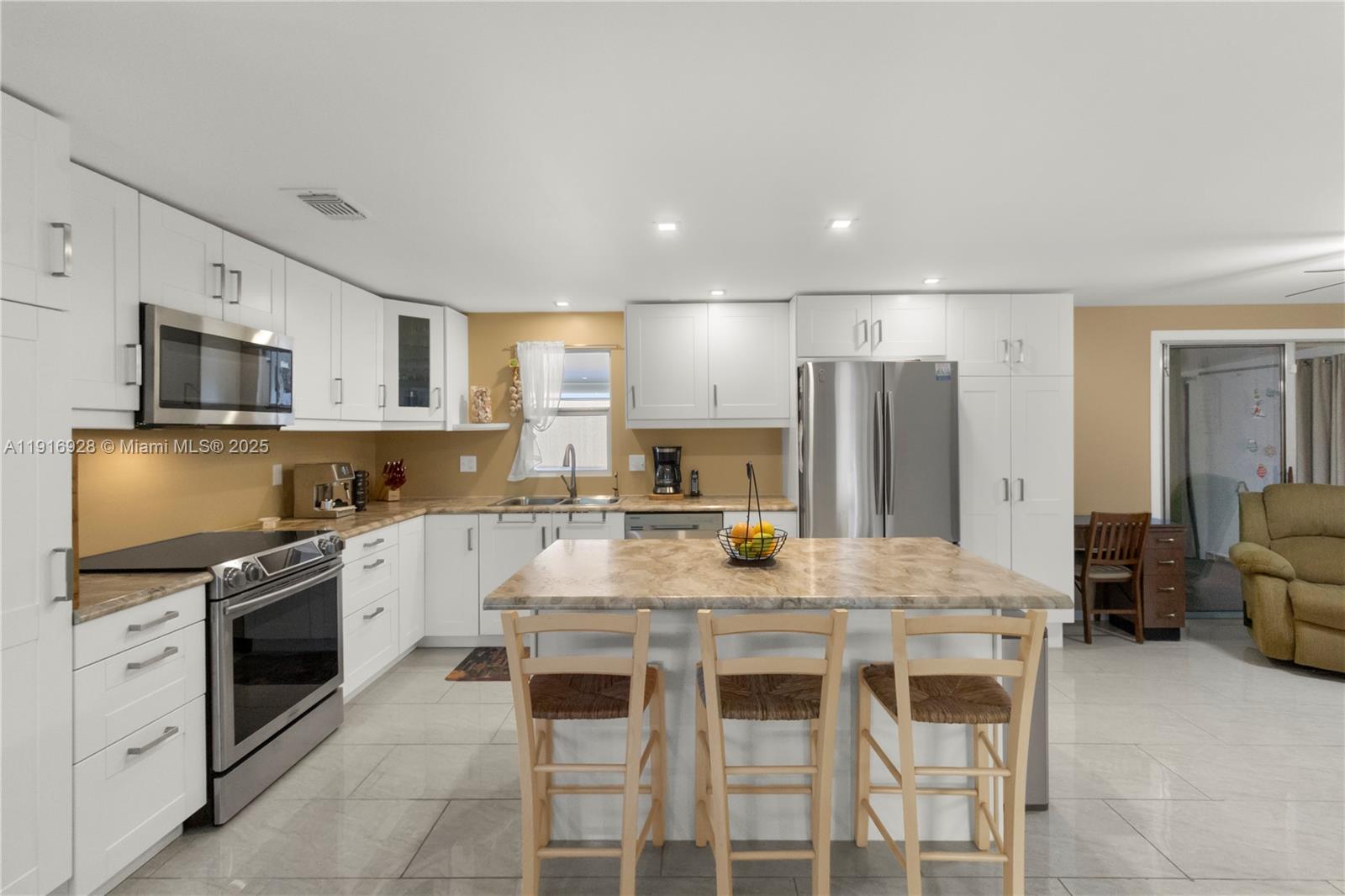 A kitchen features white cabinets, stainless steel appliances, a marble-patterned island, and light tile flooring — 5239 NW 3rd Ave, Deerfield Beach FL 33064, DEERFIELD BEACH, FL