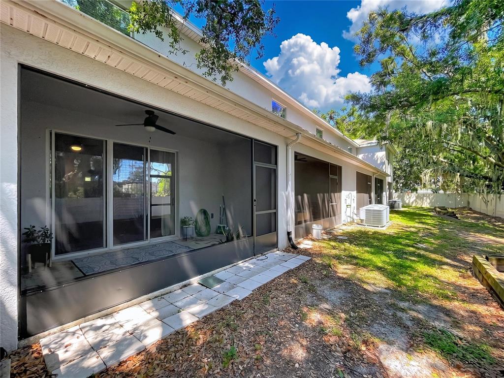 A screened-in patio with a ceiling fan overlooks a grassy backyard with air conditioning units — 3313 PLEASANT WILLOW COURT, BRANDON, FL