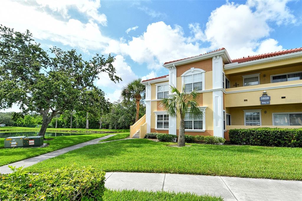A multi-story apartment building with tan stucco walls and a red tile roof — 1010 VILLAGIO CIRCLE UNIT 201, SARASOTA, FL