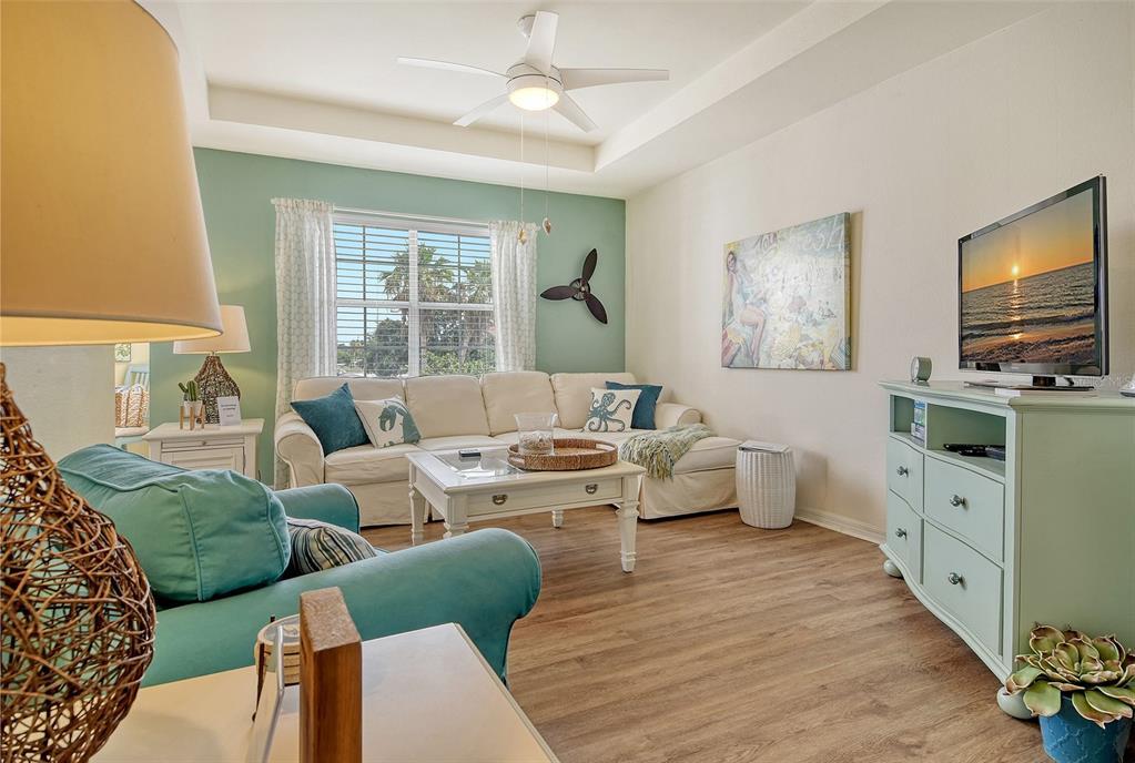 A living room features a white sofa, a teal accent wall, and a light wood floor — 1010 VILLAGIO CIRCLE UNIT 201, SARASOTA, FL