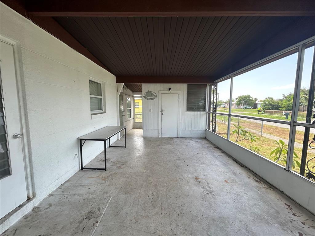 A screened-in porch features a concrete floor, white walls, and a dark wood ceiling — 3140 CRESTWOOD DRIVE, PORT CHARLOTTE, FL
