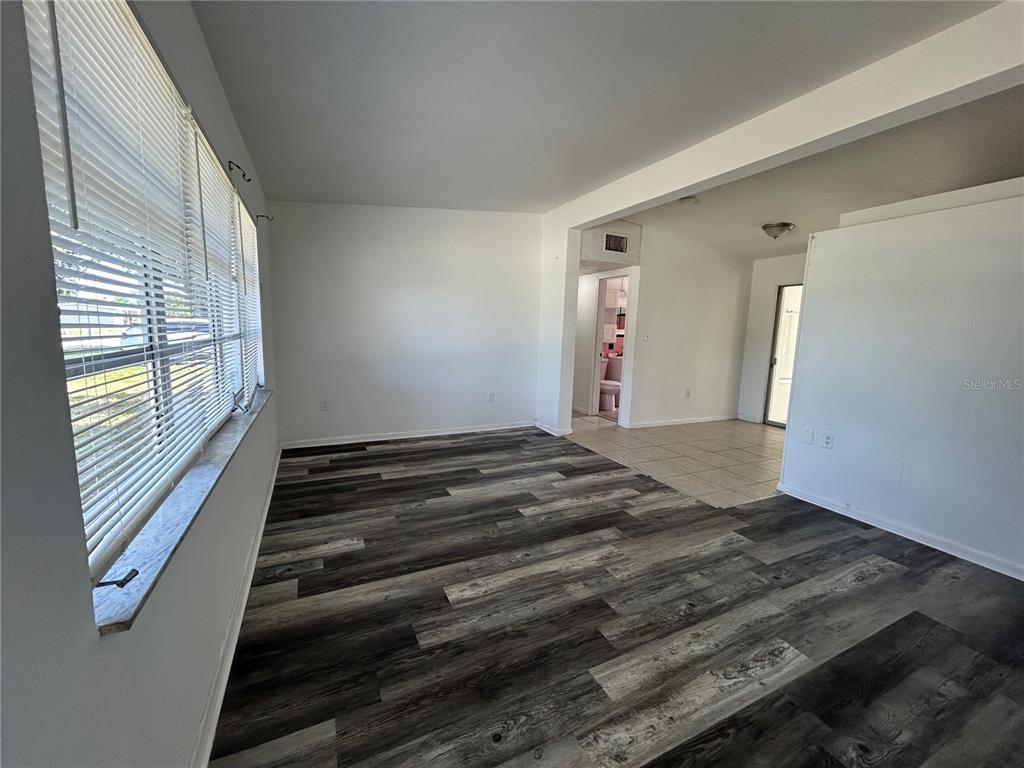 An empty room features wood-look laminate flooring, white walls, and a large window with blinds — 3140 CRESTWOOD DRIVE, PORT CHARLOTTE, FL