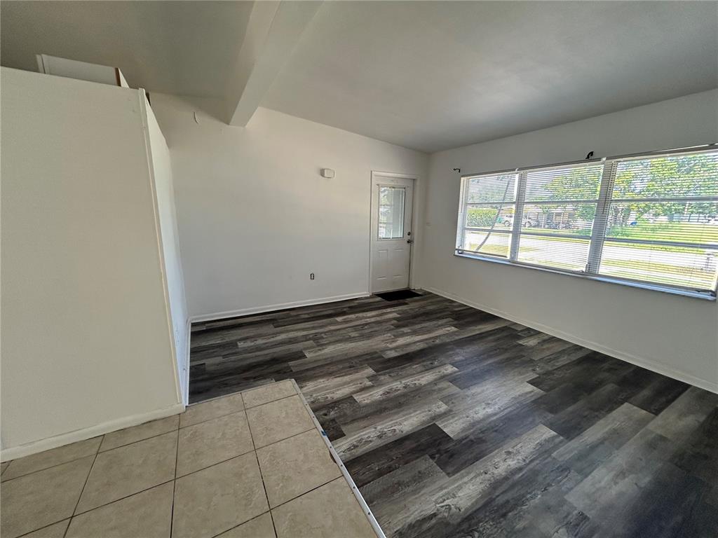An empty room features wood-look vinyl flooring, white walls, a glass-paneled door, and large windows — 3140 CRESTWOOD DRIVE, PORT CHARLOTTE, FL