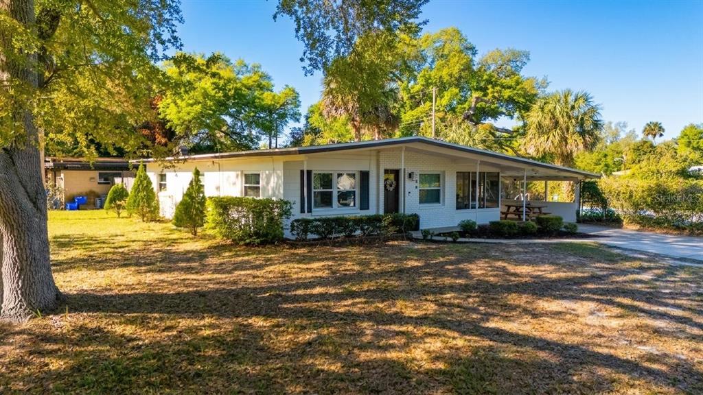 A single-story white brick house with a flat roof and a covered side patio — 106 E JINKINS CIRCLE, SANFORD, FL