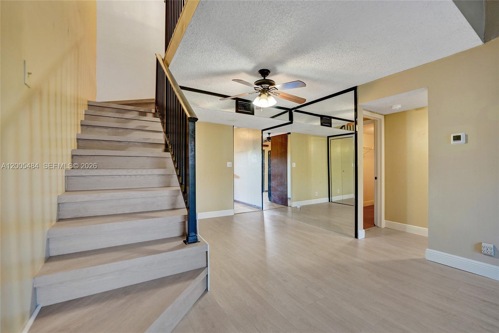 A staircase with light wood steps stands next to a room with mirrored walls — 11154 NW 37th St, Sunrise FL 33351, SUNRISE, FL