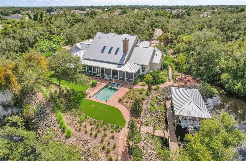An aerial view shows a house with a metal roof, pool, and boat dock — 27300 EGRET PLACE, PUNTA GORDA, FL