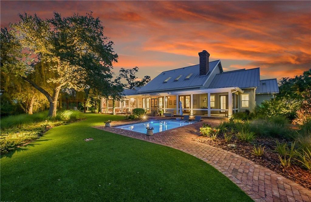 A house with a metal roof and a pool sits on a lawn at sunset — 27300 EGRET PLACE, PUNTA GORDA, FL